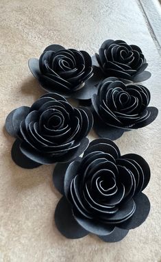 four black paper flowers sitting on top of a table