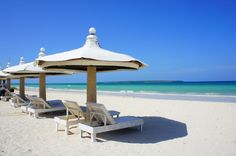 several lounge chairs and umbrellas on the beach