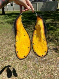 someone is holding up two yellow and black pieces of animal fur that have holes in them