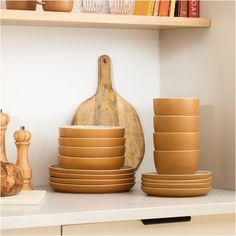 there are many brown bowls and plates on the shelf next to each other in this kitchen