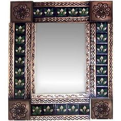 a decorative mirror with flowers and leaves painted on it's sides, sitting against a white wall