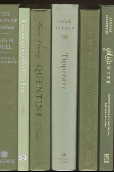 a row of green books sitting on top of a wooden book shelf next to each other