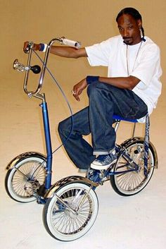 a man sitting on top of a blue bike with no wheels and wearing headphones