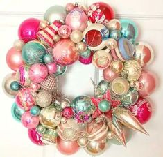 a christmas wreath with ornaments hanging on the front door, decorated in pink and blue