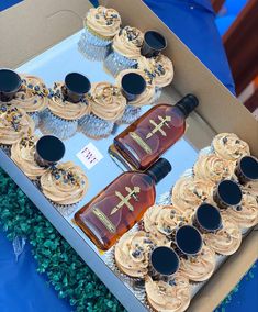 cupcakes and bottles of whiskey are on display in a box with frosted cupcakes