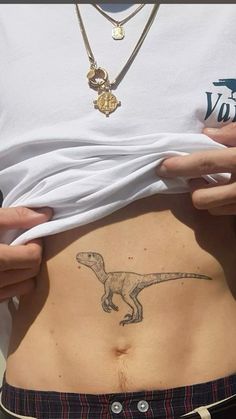 a person holding their stomach with a dinosaur tattoo on it's side and the bottom part of his stomach