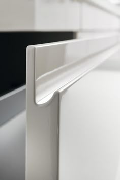 a close up view of the corner of a white cabinet door with a black background