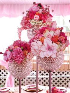 two vases filled with pink flowers sitting on top of a table next to each other