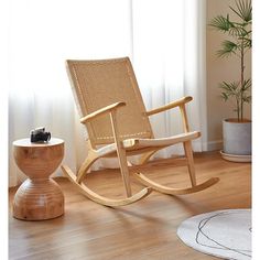 a wooden rocking chair sitting on top of a hard wood floor next to a potted plant