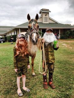 two people standing next to a horse in the grass