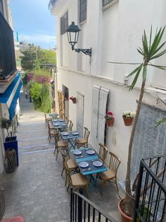 an alleyway with tables and chairs lined up on the side of the street in front of a building