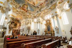 the interior of an old church with ornate paintings on the ceiling and pews in it