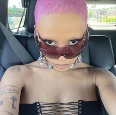 a woman with pink hair in a car wearing a mask on her face and eyeliners