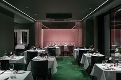 an empty restaurant with tables and chairs covered in white tablecloths, green carpeted floor