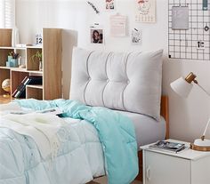 a bed with blue and white comforter in a bedroom next to a book shelf