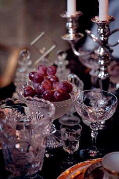 a table topped with glasses and plates filled with grapes