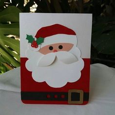 a christmas card with a santa claus face and holly berry on the front, sitting on a table