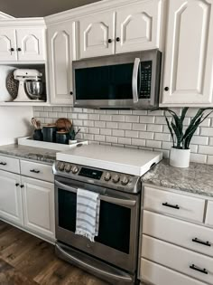 a kitchen with white cabinets and stainless steel appliances