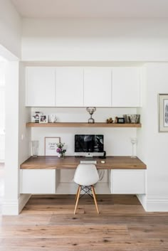 a desk with a computer on top of it in front of a wall mounted shelf