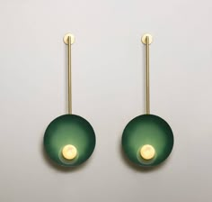 two green lights are hanging on the wall next to each other in front of a white background