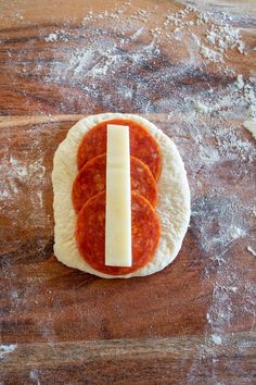 a piece of bread with cheese and tomato sauce on it sitting on a wooden surface