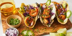 shrimp tacos with slaw, cilantro, and jalapenos on a cutting board