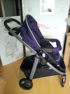 a purple stroller sitting on top of a wooden floor