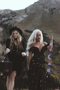 two women dressed in black are walking down the hill with one holding a bag and another carrying a purse