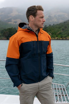 a man in an orange and blue jacket standing on a boat