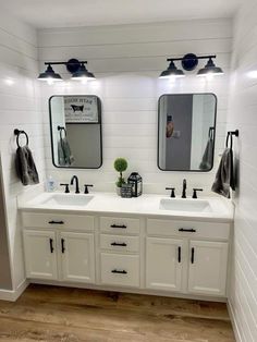 a bathroom with two sinks, mirrors and lights on the wall above them is decorated in black and white