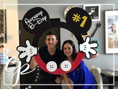 a man and woman are posing for a photo in front of mickey mouse magnets