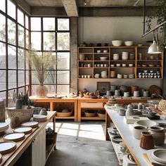 a room filled with lots of pots and pans on top of wooden shelves next to windows