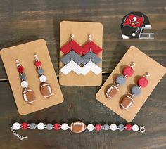 three earrings with footballs and mountains on them