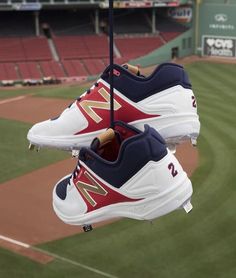 two new balance shoes hanging from a baseball field