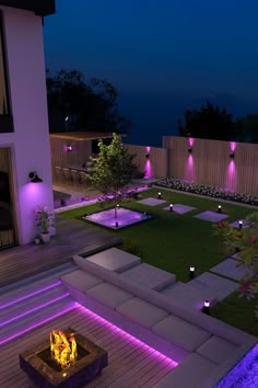 a fire pit in the middle of a yard at night with purple lights on it