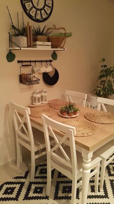 a dining room table and chairs in front of a clock on the wall above it