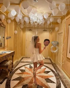 a man and woman are standing in a hallway with balloons hanging from the ceiling above them