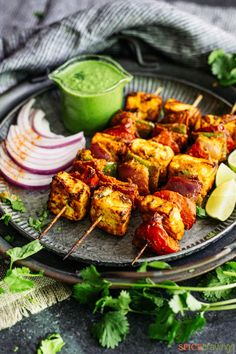 several skewers of food on a plate with onions and cilantro sauce