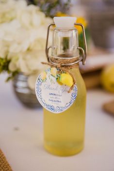 a glass bottle filled with liquid sitting on top of a table next to white flowers