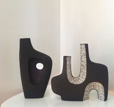 two black vases sitting on top of a white table