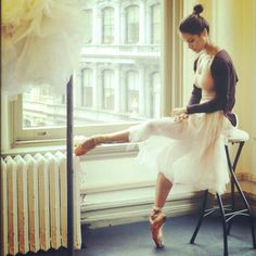 a woman sitting on top of a chair next to a window