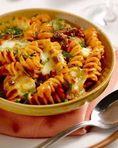 a bowl filled with pasta and vegetables on top of a plate next to a glass of wine