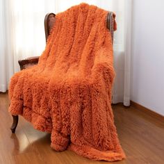 an orange fluffy blanket sitting on top of a wooden chair