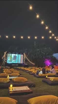 people are sitting on bean bags watching movies in the dark with lights strung over them