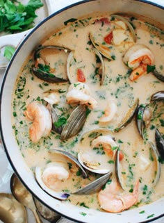 a pot filled with seafood and clams in white sauce on top of a table