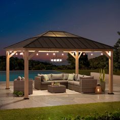 an outdoor living area with couches and lights on the patio at night time, next to a swimming pool