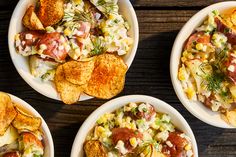 four bowls filled with different types of food on top of a wooden table next to potato wedges