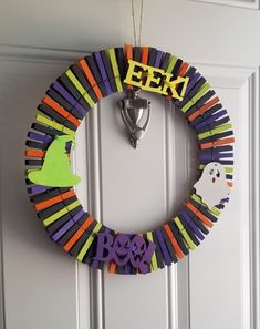 a colorful wreath hanging on the front door decorated with halloween decorations and letters that spell eek