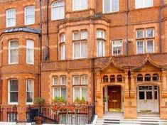 an old brick building with many windows and steps leading up to the front door,