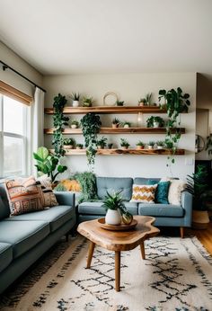 a living room filled with furniture and lots of greenery on the shelves above it